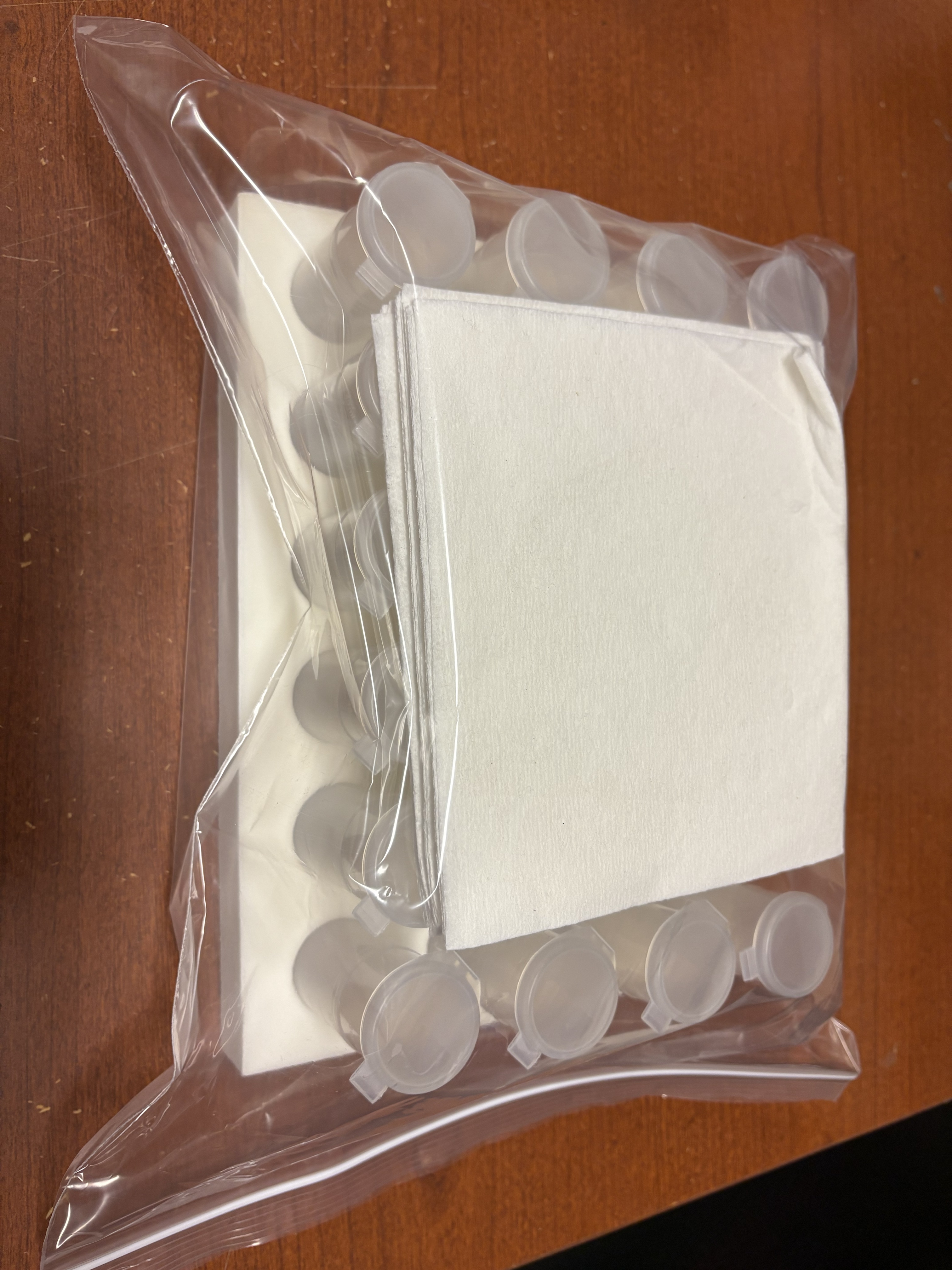 Racked sample tubes enclosed inside a sealed plastic bag along with white absorbent paper to contain leaks.
