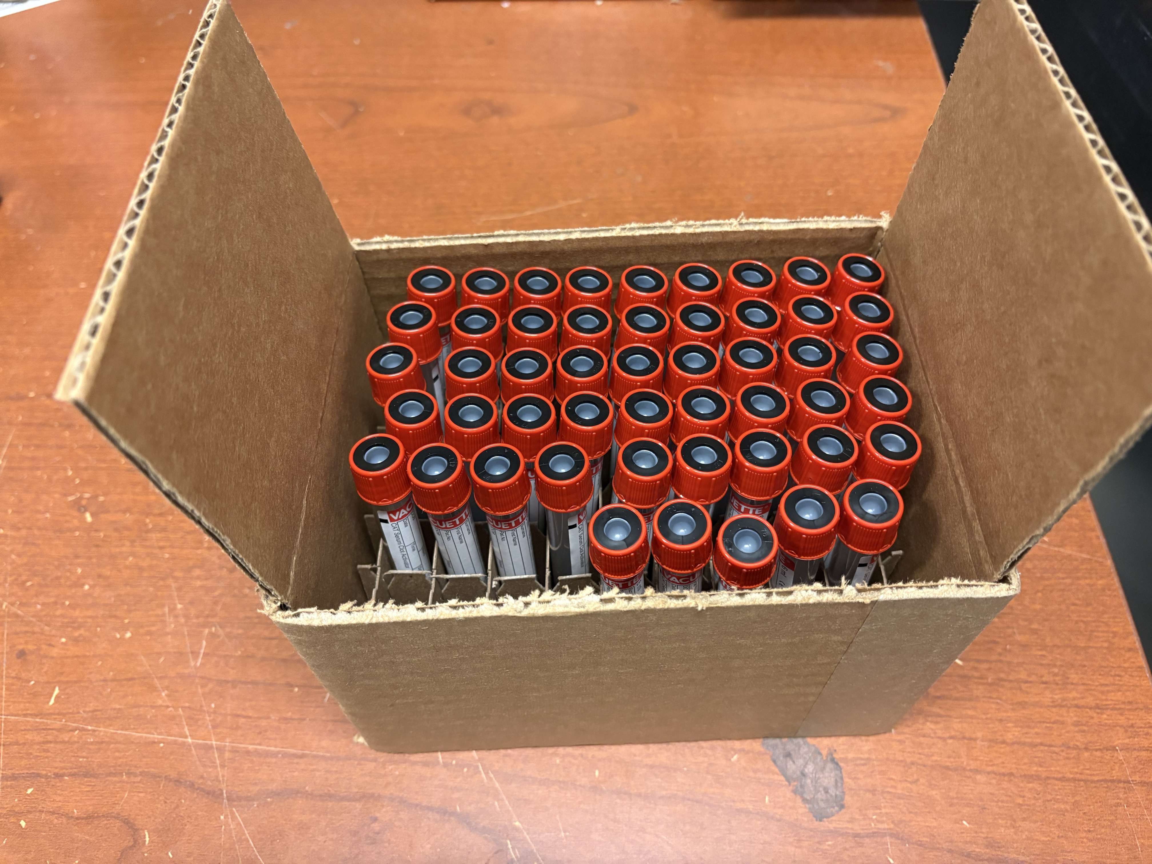 Cardboard blood tube shipper containing filled blood collection tubes.