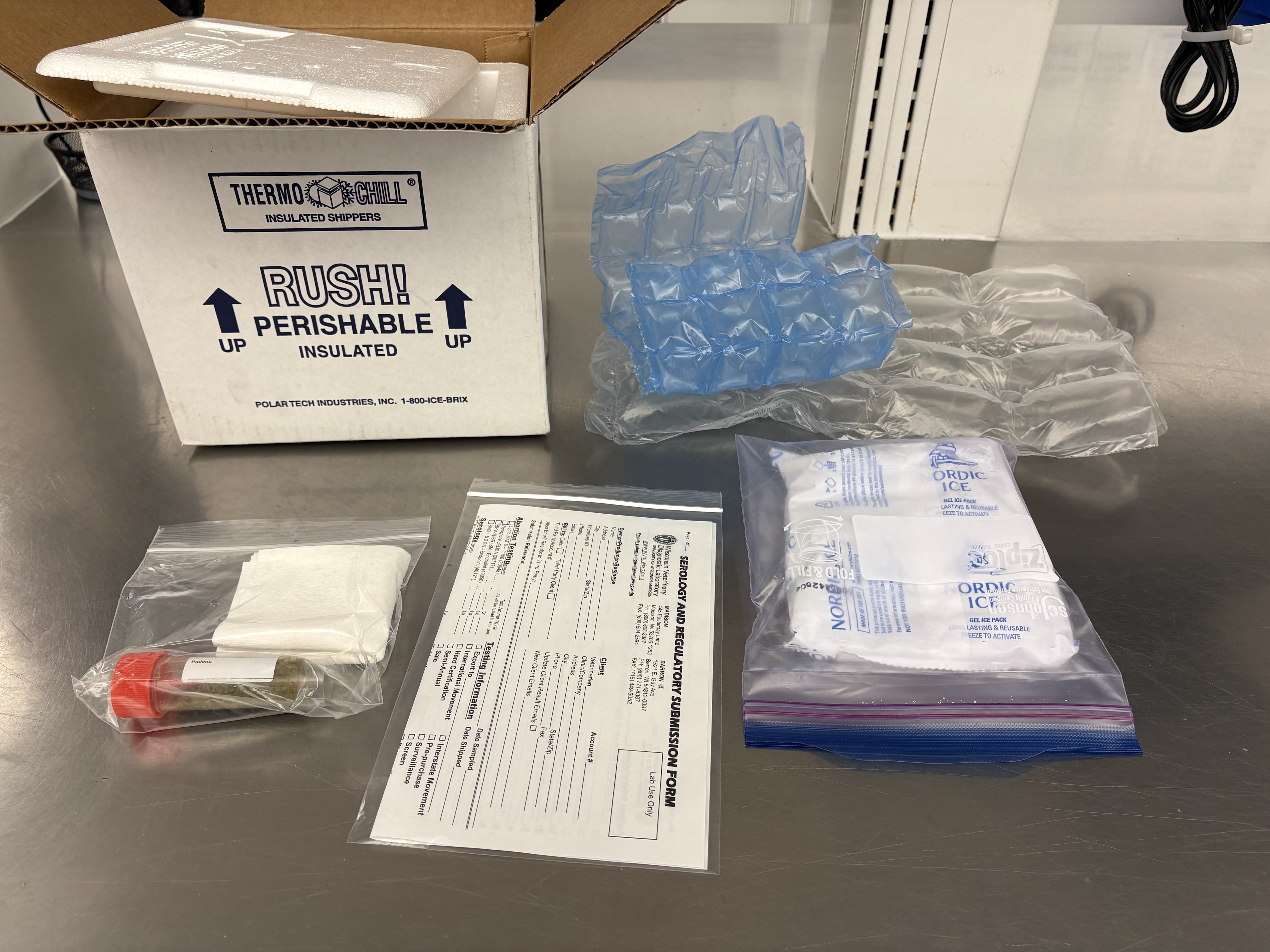 Assorted shipping supplies laid out, including an insulated box labeled 'Thermo Chill RUSH! PERISHABLE INSULATED', frozen gel packs, zip bags, and paperwork.